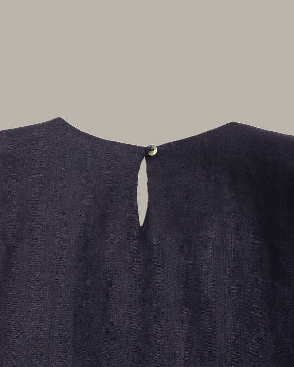 Navy blue garment with a button on a gray background