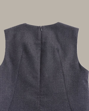 Close-up back view of a sleeveless dark gray textured vest or top, showing a center back zipper and seam details against a solid beige background.