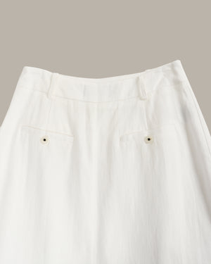 Close-up of a white skirt with buttons on a neutral background
