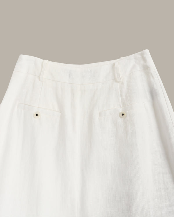 Close-up of a white skirt with buttons on a neutral background