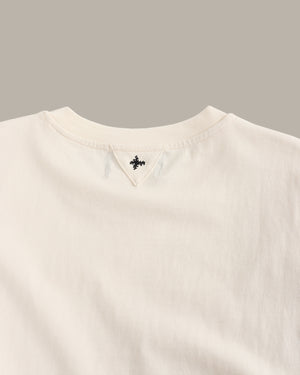 Close-up of a beige sweater with a brand logo on a gray background