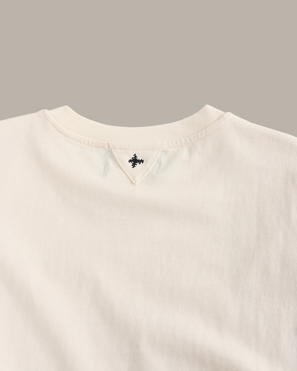 Close-up of a beige sweater with a brand logo on a gray background