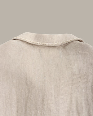 Close-up of a back of the linen jacket against a dark background with a plant.