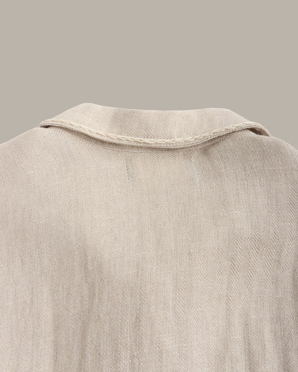 Close-up of a back of the linen jacket against a dark background with a plant.