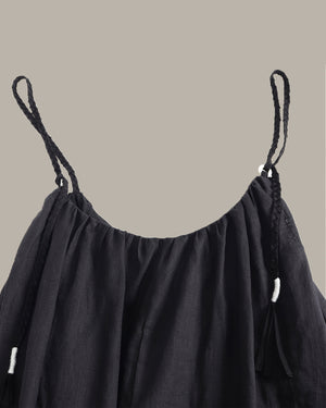 Black dress with thin straps on a beige background