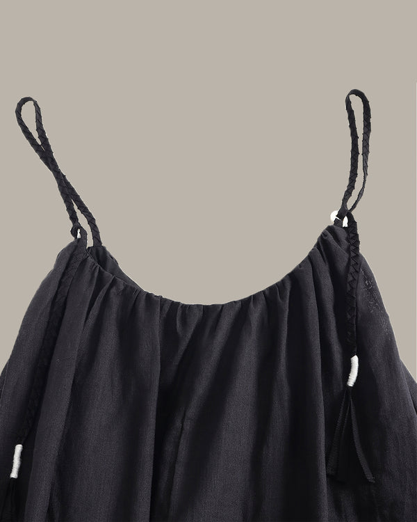 Black dress with thin straps on a beige background