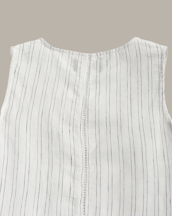 White sleeveless top with thin black stripes on a beige background