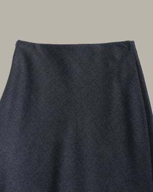 Close-up of a dark navy blue textured fabric, likely a skirt or garment, against a solid light gray background.