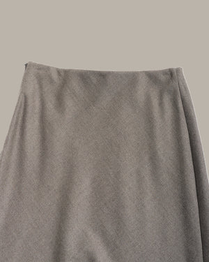 A close-up of a textured gray skirt showing the waistband and drape of the fabric against a solid neutral background.
