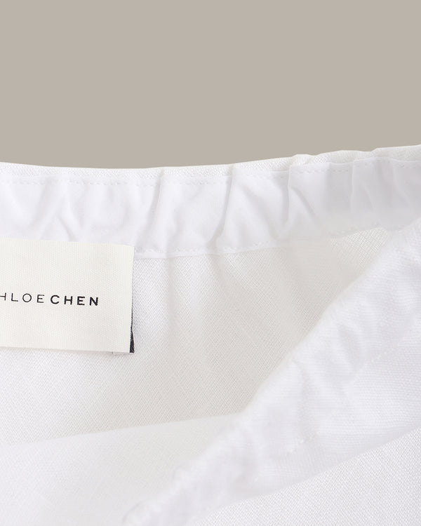 Close-up of a white skirt with 'Chloe Chen' label on a beige background