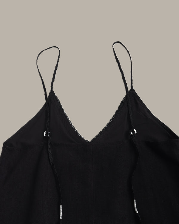 Black spaghetti-strap camisole top with delicate lace trim along the V-neckline, shown against a solid taupe background.