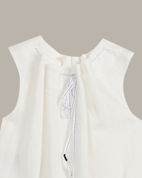 Close-up of a white sleeveless top with a subtle pattern on a beige background