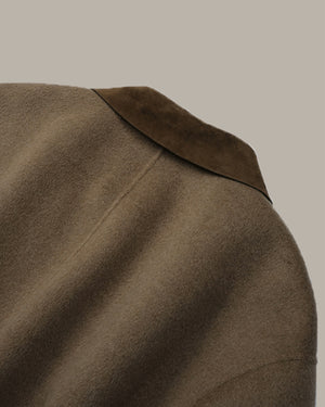 Close-up of a brown wool-like coat with a darker brown suede collar, shown against a solid light gray background.