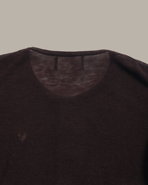Close-up of a dark brown crew-neck knit top showing the inner collar and shoulder area against a solid taupe background.