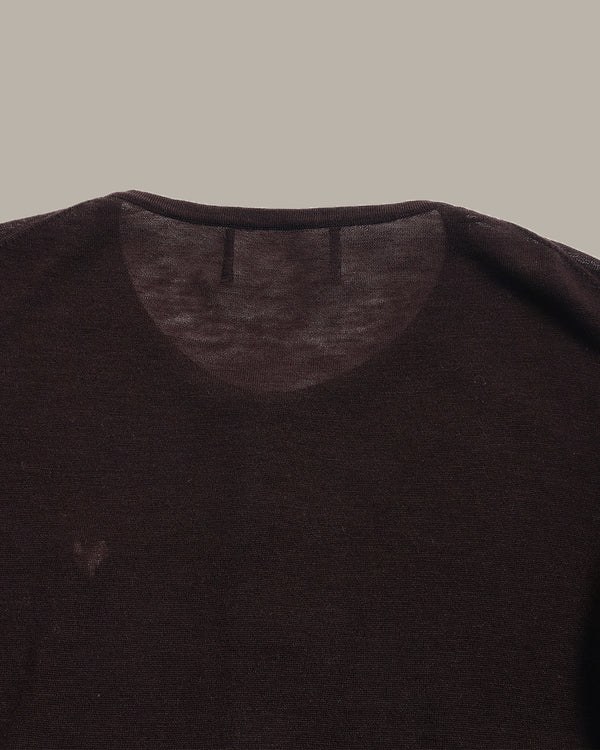 Close-up of a dark brown crew-neck knit top showing the inner collar and shoulder area against a solid taupe background.
