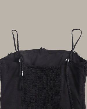 Black sleeveless top with textured design on a beige background