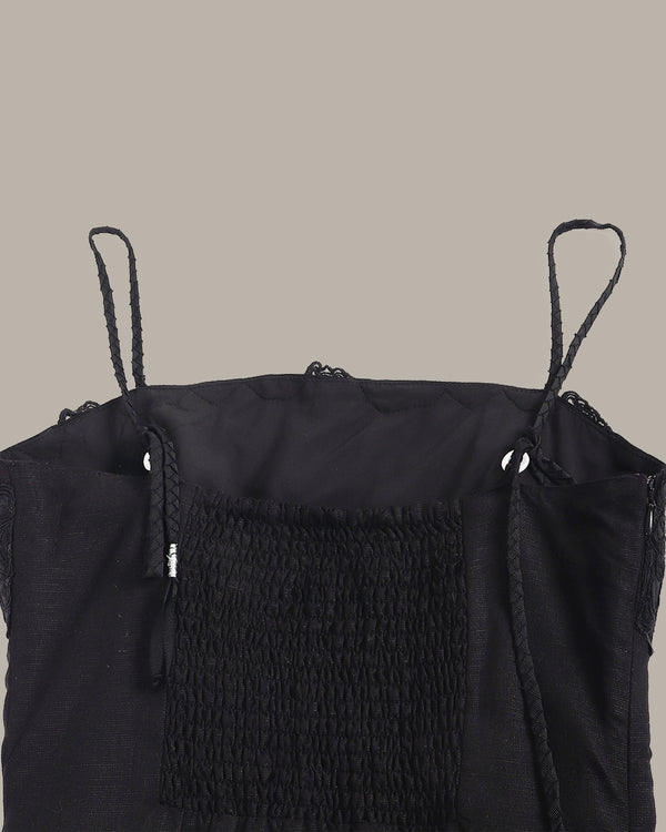 Black sleeveless top with textured design on a beige background