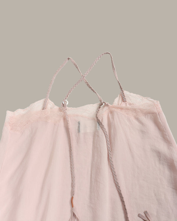 A pale blush pink sheer mesh camisole top with braided rope straps and delicate lace trim, shown against a solid taupe background.