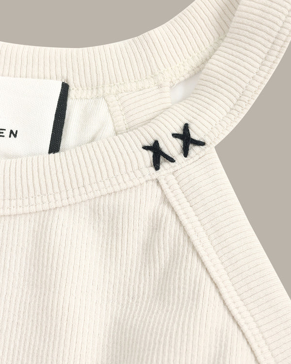 Close-up of a white ribbed sweater with black 'XX' logo on a gray background