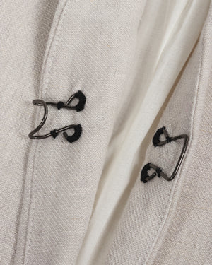 Close-up of a light gray coat with black buttons on a matching fabric background