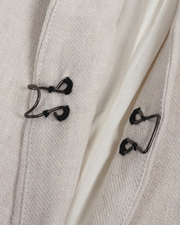 Close-up of a light gray coat with black buttons on a matching fabric background