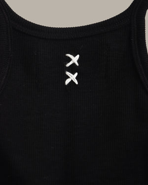 Black tank top with white embroidered design on a beige background