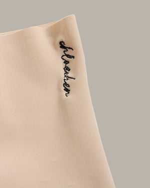 Beige fabric with black embroidered text on a neutral background