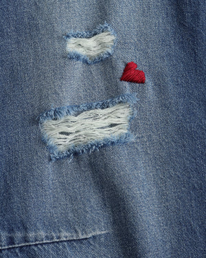 Close-up of a blue denim jacket with patches and a red heart.