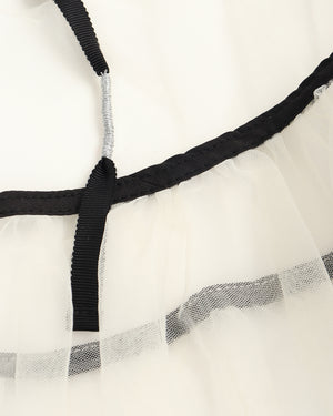 Close-up of a sheer white fabric with black elastic band and silver metal rod.