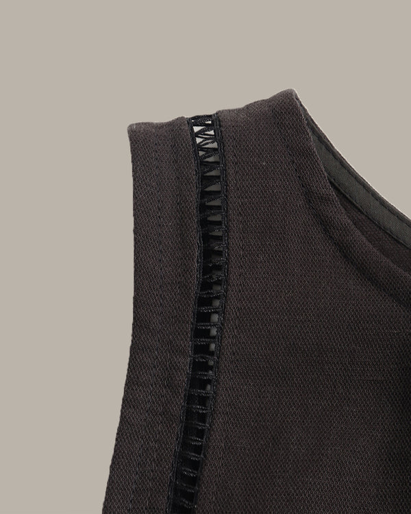Close-up of a dark gray sleeveless top with black zipper on a beige background