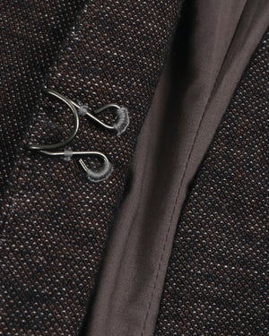 Close-up of a embroidered button textured fabric with a decorative metal brooch.