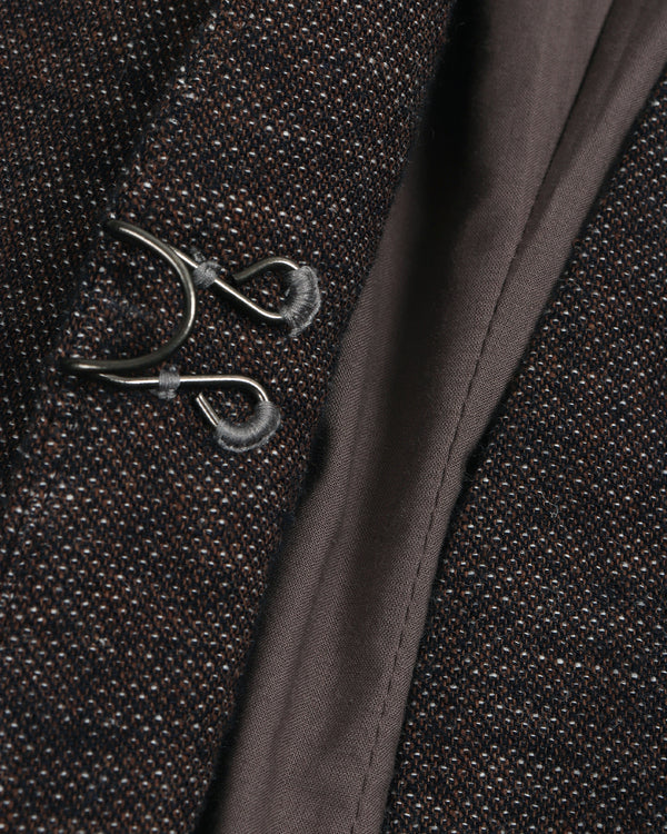 Close-up of a embroidered button textured fabric with a decorative metal brooch.