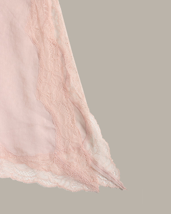 A close-up of a light pink sheer fabric with delicate lace trim, shown against a solid taupe-gray background.