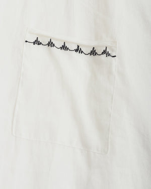 Close-up of a white fabric pocket with a black heartbeat line embroidered across the top edge.