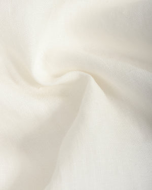 A close-up of draped off-white fabric with soft folds and a subtle woven texture.