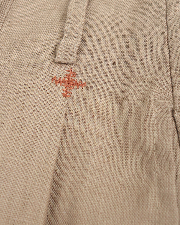 Close-up of a beige fabric with a small embroidered design on a plain background