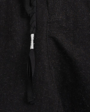Close-up of a black textured fabric with a tassel on a dark background