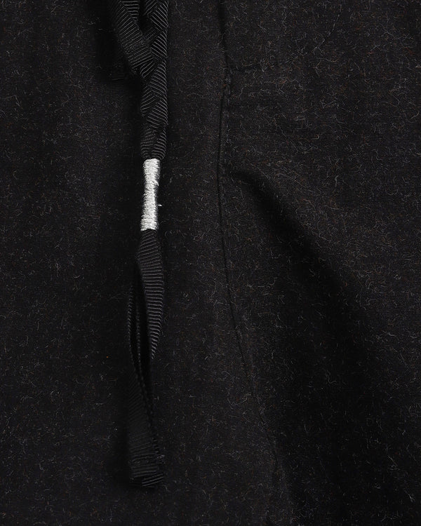 Close-up of a black textured fabric with a tassel on a dark background