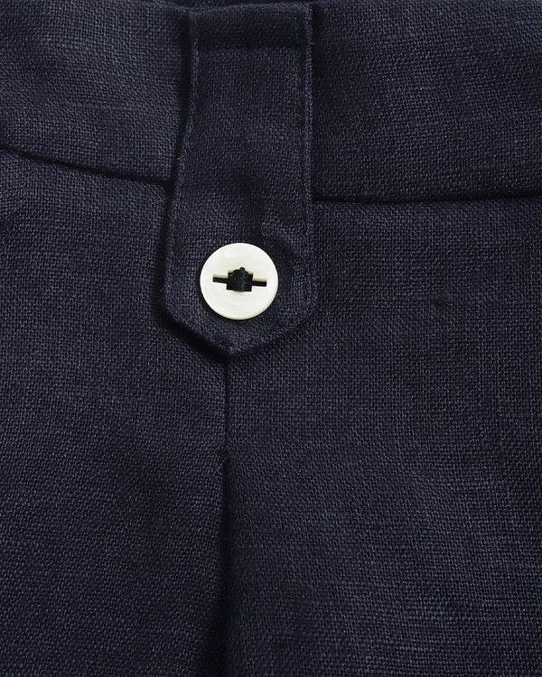 Close-up of dark navy trousers showing the waistband, belt loop, and a white button closure.