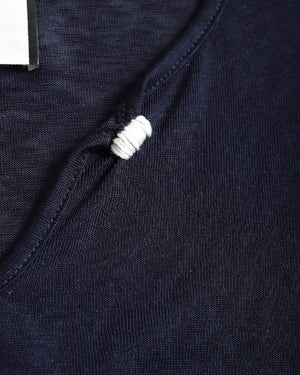 Close-up detail of a dark navy knit garment with a white ribbed trim accent along the neckline.