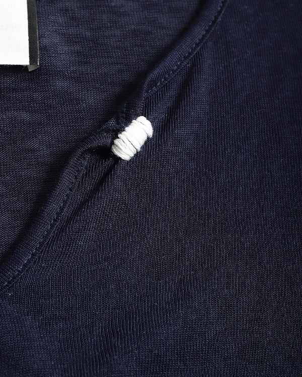 Close-up detail of a dark navy knit garment with a white ribbed trim accent along the neckline.