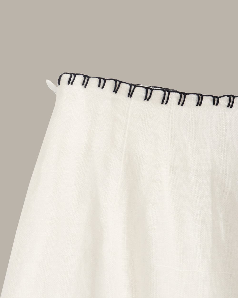 White skirt with black trim on a beige background