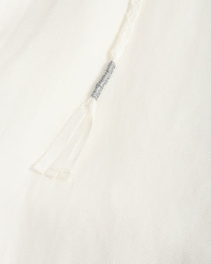Close-up of a white textured fabric garment with a drawstring detail and a small gray embroidered accent.