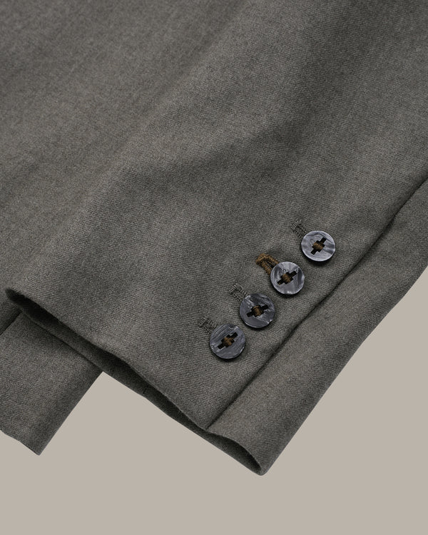 Close-up of a folded gray wool-blend blazer sleeve showing the buttoned cuff and fabric texture against a solid neutral background.