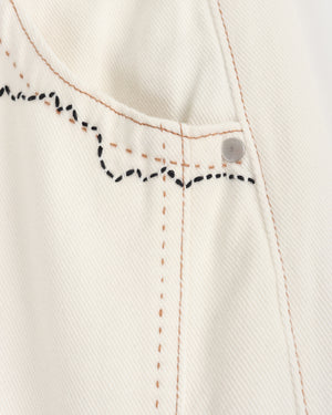Close-up of a white denim fabric with black stitching details on a light gray background