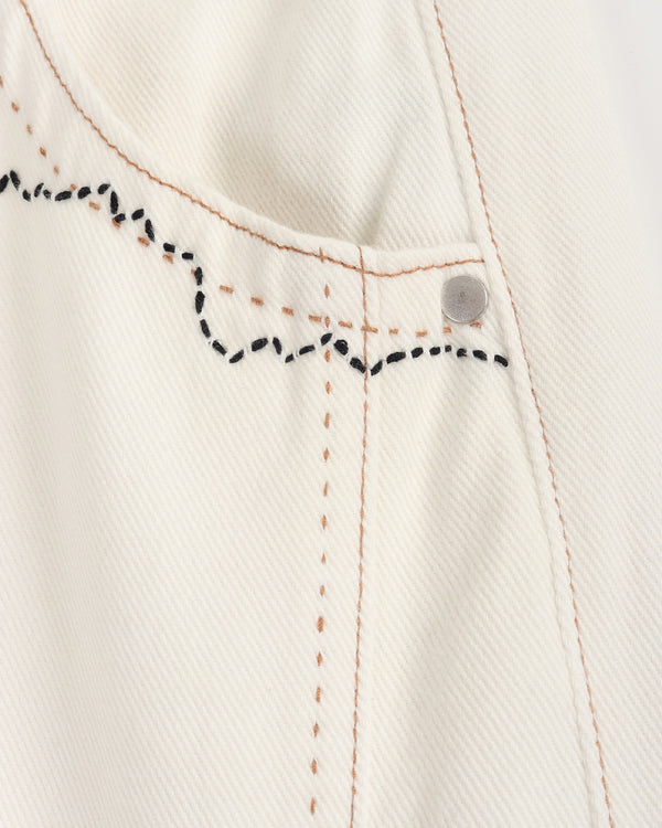 Close-up of a white denim fabric with black stitching details on a light gray background