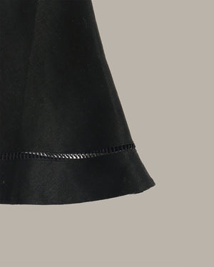 Close-up of a black skirt with a textured edge on a beige background
