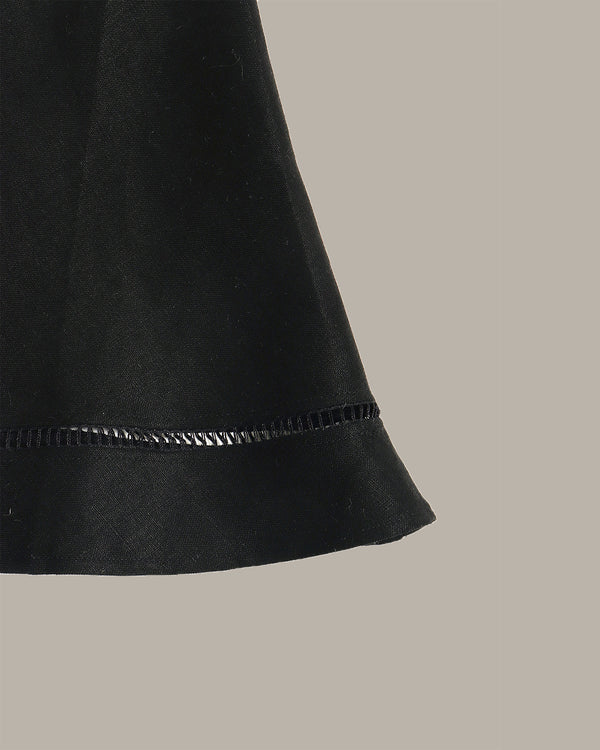 Close-up of a black skirt with a textured edge on a beige background