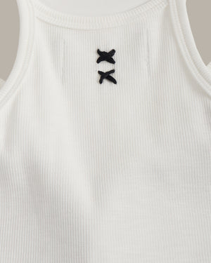 White ribbed tank top with black decorative buttons on a neutral background