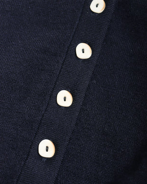 Close-up of a dark navy knit garment with a vertical row of round off-white buttons.